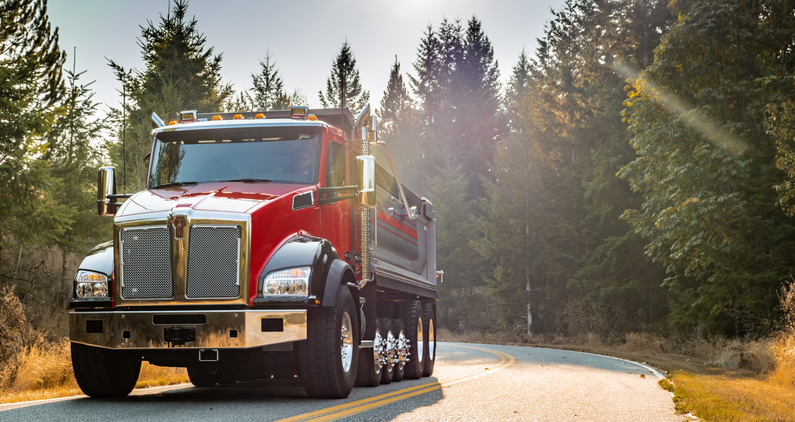 Papé Kenworth truck driving on an open road in spring conditions, representing driver wellness and staying alert on long hauls